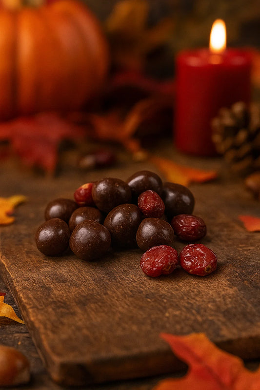 Chocolate-covered treats and dried cranberries on a wooden board with autumn decor and lit red candle